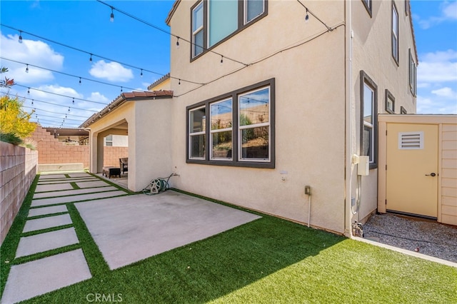 back of property with a lawn, a patio, fence, and stucco siding