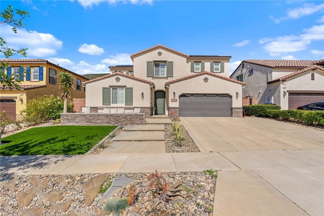 mediterranean / spanish house featuring concrete driveway, stone siding, a tiled roof, stucco siding, and a front yard