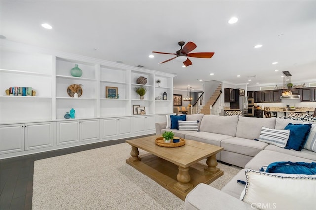 living room featuring recessed lighting, dark wood-type flooring, a ceiling fan, stairs, and crown molding