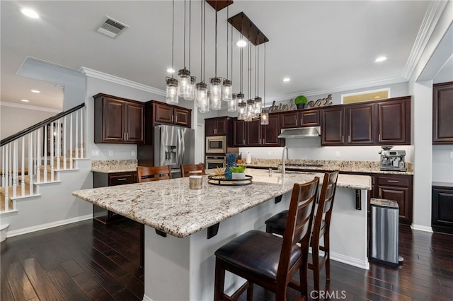 kitchen featuring stainless steel appliances, dark wood-type flooring, visible vents, and under cabinet range hood