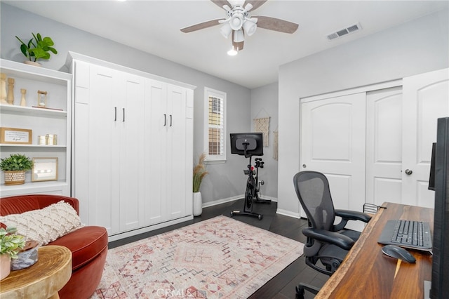 office space with visible vents, dark wood-style flooring, a ceiling fan, and baseboards