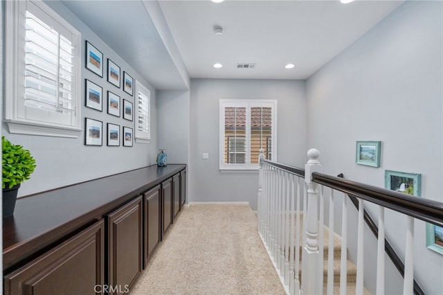 hallway with visible vents, baseboards, light colored carpet, an upstairs landing, and recessed lighting