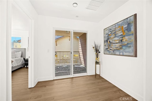 doorway featuring baseboards, visible vents, and wood finished floors