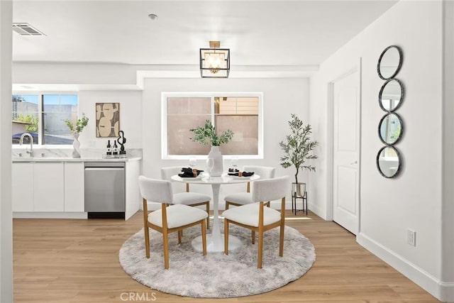 dining room with light wood-style floors, visible vents, and baseboards