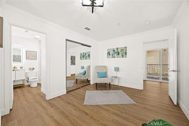 living area with baseboards, light wood-style flooring, visible vents, and crown molding