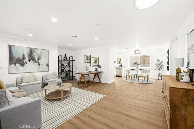 living room featuring visible vents, baseboards, light wood-style flooring, and recessed lighting