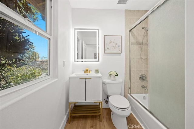 bathroom featuring baseboards, toilet, wood finished floors, vanity, and washtub / shower combination