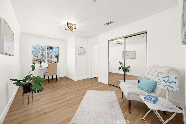 sitting room with ornamental molding, light wood-type flooring, visible vents, and baseboards