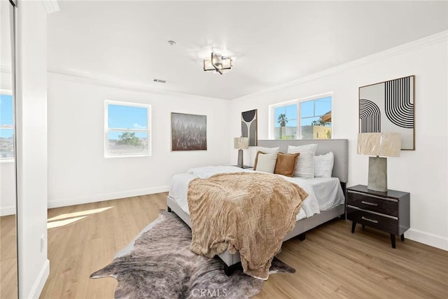 bedroom featuring multiple windows, crown molding, visible vents, and wood finished floors