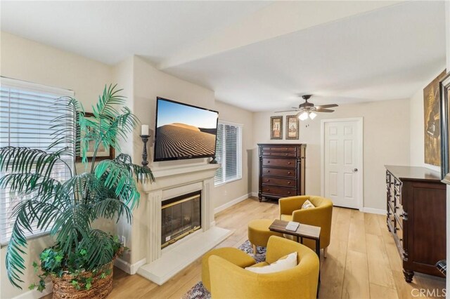 25 Vista Toscana, Lake Elsinore, CA 92532 - living area with light wood-style floors, a glass covered fireplace, ceiling fan, and baseboards