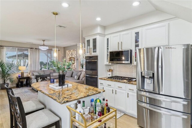 25 Vista Toscana, Lake Elsinore, CA 92532 - kitchen featuring stainless steel appliances, light stone countertops, white cabinetry, light wood-style floors, and a kitchen breakfast bar