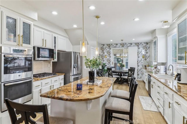 25 Vista Toscana, Lake Elsinore, CA 92532 - kitchen with stainless steel appliances, a sink, a kitchen breakfast bar, light stone countertops, and a center island