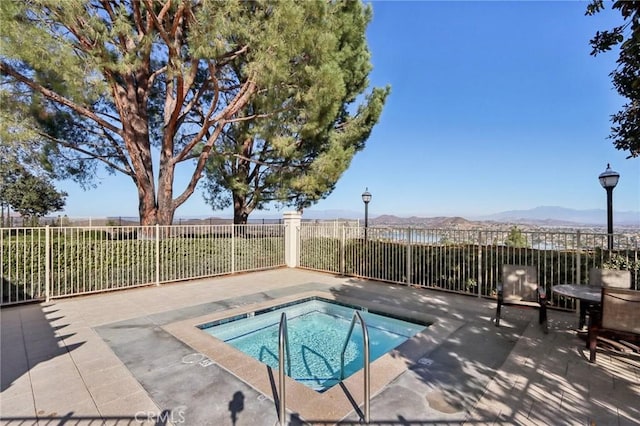 view of pool with a patio, a mountain view, a community hot tub, and fence