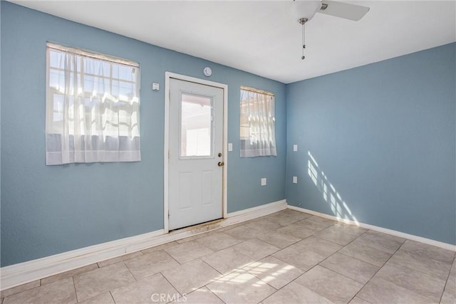 doorway featuring tile patterned flooring, plenty of natural light, baseboards, and ceiling fan