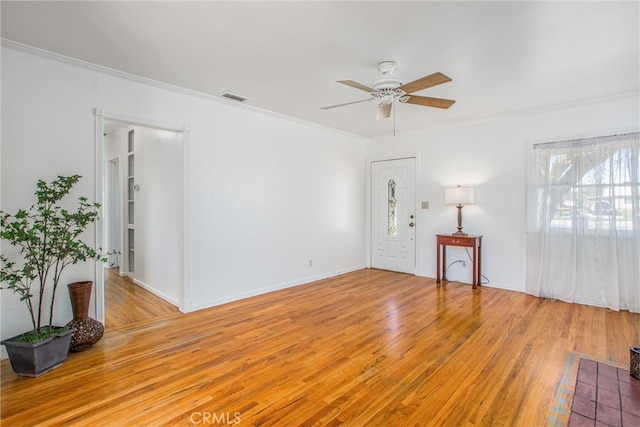 interior space with a ceiling fan, visible vents, light wood finished floors, baseboards, and crown molding