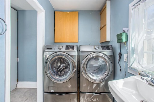 laundry area featuring a sink, baseboards, separate washer and dryer, and tile patterned flooring