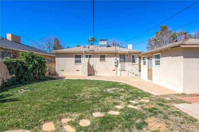 back of property with stucco siding, central air condition unit, a yard, and a patio area