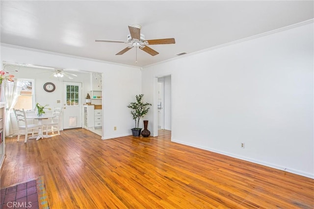 unfurnished living room featuring visible vents, ceiling fan, baseboards, ornamental molding, and wood-type flooring