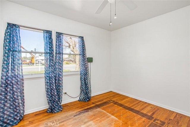 unfurnished room featuring a ceiling fan, wood finished floors, and baseboards