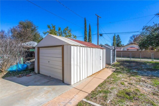 detached garage with a shed, fence, and driveway