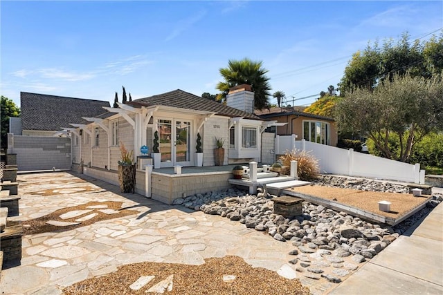 exterior space featuring fence, french doors, and a chimney