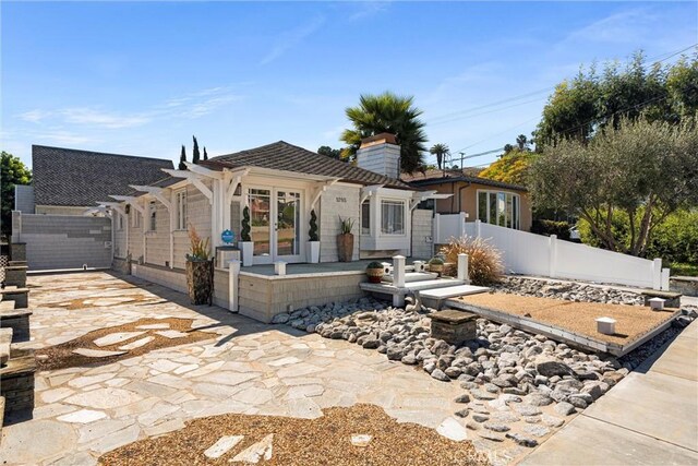 back of house with fence, a chimney, french doors, and a patio area