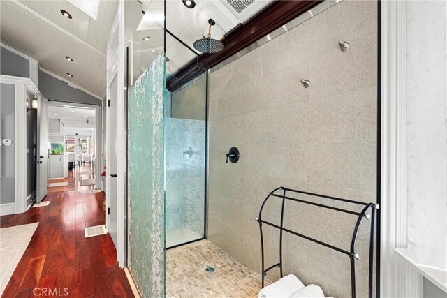 bathroom featuring a walk in shower, wood finished floors, visible vents, baseboards, and lofted ceiling