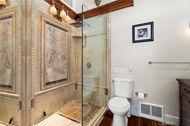 full bath featuring visible vents, toilet, tiled shower, wood finished floors, and vanity