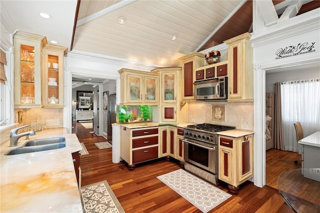 kitchen with dark wood finished floors, a sink, vaulted ceiling, light countertops, and appliances with stainless steel finishes