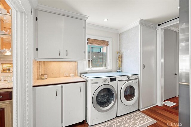clothes washing area featuring cabinet space, dark wood-type flooring, visible vents, ornamental molding, and washer and dryer
