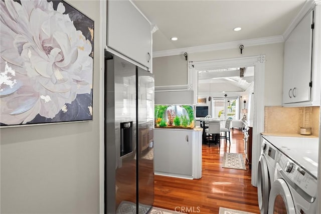 kitchen with crown molding, wood finished floors, stainless steel fridge with ice dispenser, and washer and clothes dryer