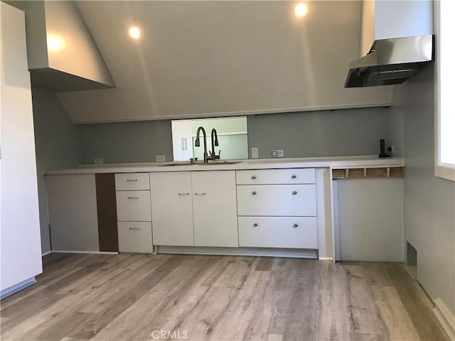 kitchen featuring white cabinetry, light countertops, light wood finished floors, and a sink