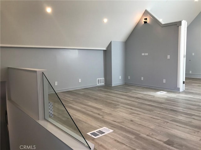 additional living space with vaulted ceiling, visible vents, baseboards, and wood finished floors