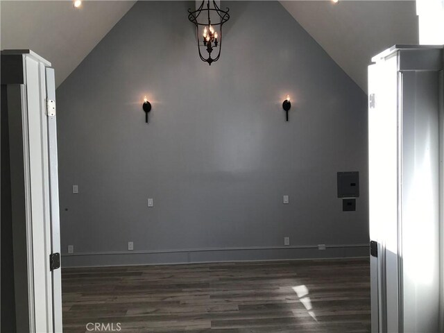 spare room with baseboards, vaulted ceiling, and dark wood-type flooring