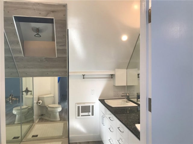 full bathroom with a sink, heating unit, toilet, a shower with shower door, and double vanity