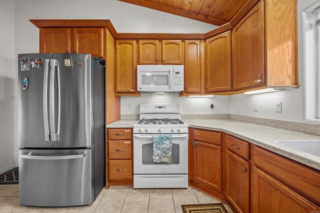 kitchen featuring white appliances, brown cabinetry, lofted ceiling, light tile patterned flooring, and light countertops