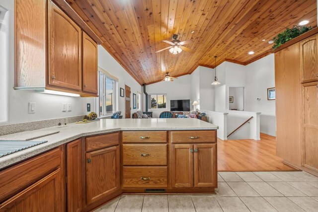 kitchen featuring light tile patterned floors, a peninsula, light countertops, vaulted ceiling, and open floor plan