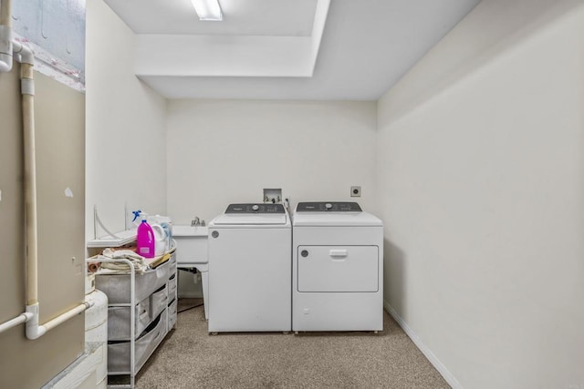 clothes washing area featuring laundry area, washing machine and dryer, light colored carpet, and baseboards