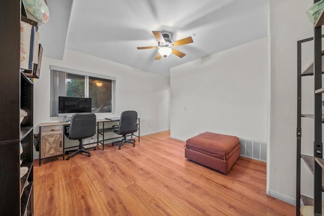 office area with baseboards, light wood-style floors, visible vents, and ceiling fan