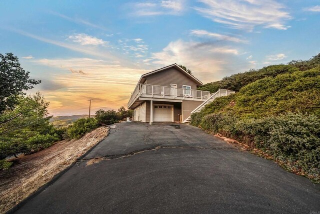 view of front of property featuring stairway, a garage, and driveway