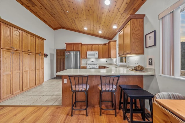 kitchen featuring wood ceiling, light countertops, lofted ceiling, a peninsula, and white appliances