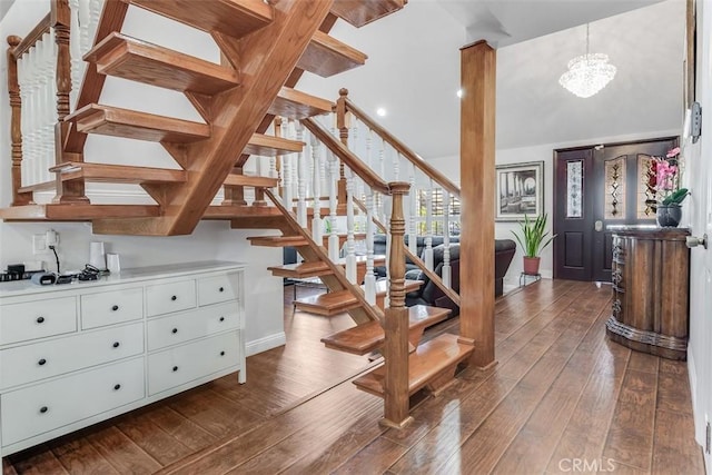 stairs featuring lofted ceiling, hardwood / wood-style flooring, and a chandelier