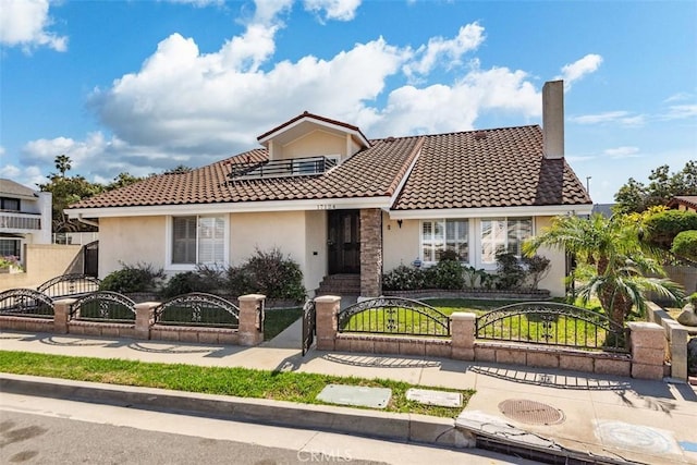 view of front of house with a fenced front yard, a gate, a tile roof, and stucco siding