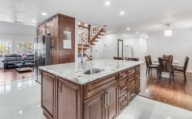 kitchen with light stone countertops, open floor plan, a sink, and freestanding refrigerator