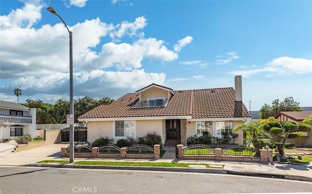 view of front of home featuring a fenced front yard, a gate, a tiled roof, and stucco siding