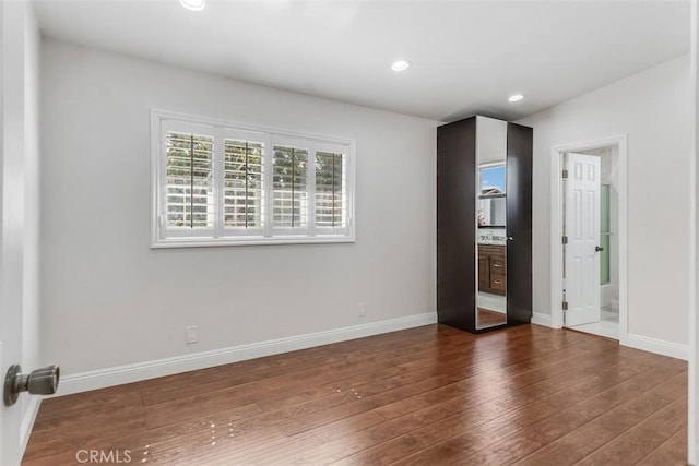 spare room featuring dark wood-style floors, recessed lighting, and baseboards