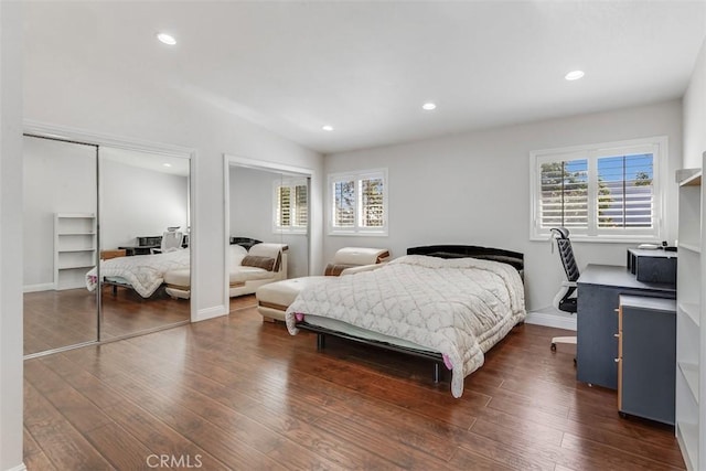 bedroom featuring lofted ceiling, wood finished floors, two closets, and recessed lighting