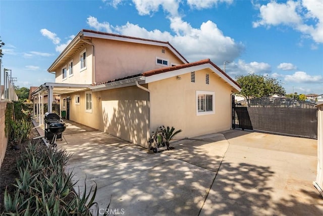 view of side of property with a gate, a patio, fence, and stucco siding