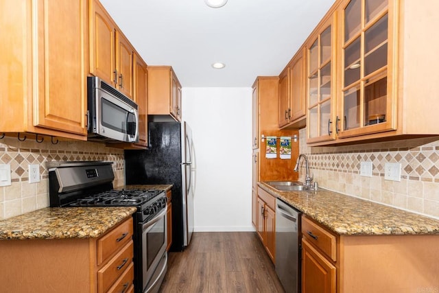 kitchen featuring light stone countertops, dark wood-type flooring, stainless steel appliances, and a sink