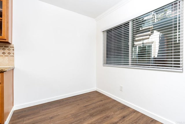 empty room featuring baseboards, dark wood finished floors, and ornamental molding